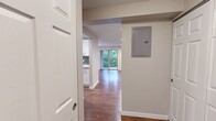 Located at 433 Bellevue Way SE in the heart of Bellevue, WA, this single-floor, three-bedroom, one-bathroom residence offers a well-designed layout with consistent hardwood flooring throughout. The combined kitchen and living room serves as the central hub of the home. The kitchen is thoughtfully appointed with crisp white cabinetry, quartz countertops, a mosaic tile backsplash, and a full suite of stainless steel appliances. The adjacent living area is bright and open, featuring recessed lighting, large sliding glass doors, and expansive windows that frame views of lush Pacific Northwest greenery and provide access to a private balcony. Each of the three bedrooms is finished with hardwood flooring and features windows that bring in natural light and outdoor views. The primary bedroom includes mirrored sliding closet doors, adding depth to the space. The full bathroom is clean and modern, outfitted with white cabinetry, brushed nickel hardware, a large vanity mirror, and a tub-shower combination accented with a mosaic tile detail. Two hallways connect the rooms efficiently, contributing to the home's practical and cohesive flow. Neutral wall tones throughout lend a calm, versatile aesthetic.
