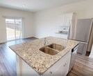 Located at 12511 Oberon in San Antonio, Texas, this two-story home offers 1,670 square feet across four bedrooms and two bathrooms. The ground floor spans 670 square feet and features an open-concept kitchen and living area with light wood-look tile flooring, white shaker cabinetry, granite countertops, and stainless steel appliances. An attached garage with an automatic opener and drywall-finished walls provides secure parking and additional storage. The upper floor encompasses 1,000 square feet and hosts all four bedrooms, two bathrooms, and a dedicated laundry room equipped with a full-size washer and dryer. The primary bedroom measures 240 square feet and includes a spacious walk-in closet with wire shelving. Secondary bedrooms feature light wood-look flooring, ceiling fans, and ample natural light from double-pane windows with blinds. Carpeted bedrooms on the upper level add comfort underfoot. Both bathrooms are finished with wood-look tile flooring, white vanities, and tub-shower combinations. The laundry room includes overhead wire shelving for added organization. Outside, the home sits on a generously sized, fully fenced backyard with a wood privacy fence, a manicured lawn, and open sky views, offering a private outdoor retreat.