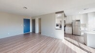 This single-floor residence offers a clean, neutral aesthetic throughout, with a layout designed to maximize functionality and natural light. The open living area is finished with light wood-style plank flooring and features a textured ceiling with integrated HVAC venting. A sliding glass door anchors one end of the living space, flooding the room with natural light and providing direct access to an outdoor area.

The kitchen is well-appointed with white shaker-style cabinetry, light quartz countertops, and a full suite of stainless steel appliances, including a gas range, refrigerator, dishwasher, and microwave. A subway tile backsplash in a soft neutral tone adds a refined touch, while a large window brings in additional daylight. A pass-through opening connects the kitchen to the main living area, enhancing the open feel of the space.

The bedroom is carpeted for comfort, features a ceiling fan with light fixture, and is brightened by a window with exterior views. Closet storage is also available. The bathroom is finished with tile flooring, a tiled walk-in shower, white vanity with a solid surface countertop, and brushed nickel fixtures, offering a clean and modern look throughout.