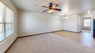 Located at 921 Cottage Park Cir in McAlester, Oklahoma, this single-story, two-bedroom, one-bathroom home offers a practical and comfortable layout. The combined kitchen and living area forms the heart of the home, with the kitchen featuring warm honey-toned wood cabinetry, laminate stone-style countertops, light wood-look flooring, and black appliances including a range, dishwasher, and refrigerator. The living area transitions seamlessly from the kitchen, with plush neutral carpeting and a ceiling fan with light fixture, creating a welcoming and functional space. Natural light filters in through windows, adding brightness throughout. Both bedrooms are carpeted and equipped with ceiling fans, providing comfort year-round. The primary bedroom offers a generous footprint with ample room for furniture arrangement. The full bathroom is notably spacious and accessibility-friendly, featuring tile flooring, grab bars, a vanity with warm wood cabinetry, and a tub/shower combination. A dedicated closet provides additional storage. The attached garage offers a roomy concrete-floored space with an automatic door opener, ideal for vehicle storage or utility use. Dark baseboards throughout the home add a clean, finished contrast to the neutral walls.