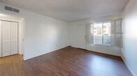 Located at 5025 N First Ave in Tucson, Arizona, this single-story, one-bedroom, two-bathroom unit offers a compact and functional layout. The living room serves as the central gathering space, featuring rich wood-look flooring, bright white walls, and a textured ceiling. A large window with shuttered blinds allows natural light to fill the room while offering views to the outdoors. The galley-style kitchen is efficiently designed with natural wood upper and lower cabinetry, white laminate countertops, a single-basin sink, and a black electric range with hood ventilation. A full-size refrigerator is also included. The bedroom is a comfortable, well-proportioned space finished with plush carpeting, a window with blinds for natural light, and direct access to a dedicated closet. Two bathrooms serve the unit; one features a wide vanity with ample counter space and a large mirror with overhead lighting, while the other includes a full soaking tub and shower combination with marble-patterned surround panels. Both bathrooms carry the same clean, neutral palette found throughout the home. Wood-look flooring flows through the main living areas, tying the space together with a warm and cohesive aesthetic.