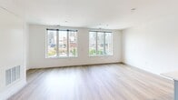 Located at 801 N Orange St in Wilmington, Delaware, this modern 1-bedroom, 1-bathroom unit offers a well-designed open-concept layout with contemporary finishes throughout. Light wood-tone flooring runs continuously across the entire space, creating a cohesive and airy feel.

The combined kitchen and living area serves as the heart of the unit. The kitchen is outfitted with sleek grey cabinetry extending to the ceiling for ample storage, white quartz countertops, stainless steel appliances including a refrigerator, range, and microwave, and a large island with an undermount sink — all accented by a modern pendant light fixture. The open living area benefits from oversized windows that frame views of the surrounding Wilmington cityscape, flooding the space with natural light.

The bedroom is a comfortable, well-proportioned room featuring its own large window with urban views and a built-in closet with shelving for organized storage.

The bathroom presents a clean, modern aesthetic with large-format tile flooring, a wood-toned vanity with white countertop and undermount sink, a framed mirror with vanity lighting, and a standard toilet.

Overall, the unit offers a bright, minimalist design well-suited for urban living in the heart of Wilmington.