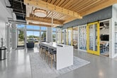 Located at 2315 South 11th Avenue in Bozeman, Montana, this thoughtfully designed collaborative space offers a dynamic environment for studying, gathering, and focused work. The single-floor layout spans a generous footprint, combining open-plan areas with enclosed private rooms to accommodate a variety of needs.

Architecturally, the space is distinguished by warm, natural wood plank ceilings with exposed structural beams and visible ductwork, creating an industrial-yet-inviting aesthetic. Polished concrete floors run throughout, providing a clean, durable surface that reflects the abundant natural light pouring in through the expansive floor-to-ceiling windows lining the perimeter walls.

The open lounge area features a central high-top bar island with bar stools, modular seating arrangements, and individual café-style tables with blue upholstered chairs — ideal for both solo work and small group collaboration. Bold, abstract graphic murals adorn the walls, adding artistic energy to the space, while motivational text is displayed prominently near the ceiling.

Enclosed private study rooms are accessible via striking yellow-framed sliding barn doors with frosted glass panels featuring artistic designs, offering visual privacy while maintaining a sense of openness. Each room is equipped with a display screen and collaborative seating. The overall ambiance is bright, modern, and energizing, designed to stimulate productivity and creativity.