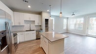 This well-appointed 1-bedroom, 1-bathroom unit offers a thoughtfully designed single-floor layout with modern finishes throughout. The open-concept kitchen serves as the centerpiece of the living area, featuring crisp white shaker-style cabinetry, a subway tile backsplash, quartz countertops, and a full suite of stainless steel appliances including a French door refrigerator with ice maker, electric range, built-in microwave, and dishwasher. A generously sized kitchen island with pendant lighting above provides additional prep space and casual seating, flowing seamlessly into the living area, which is equipped with a ceiling fan and bright windows that invite natural light. A dedicated pantry offers additional storage just off the kitchen. The bedroom is a calm, light-filled retreat with hardwood-style flooring, a ceiling fan, and a window with outdoor views. The full bathroom includes a dual-sink vanity with white cabinetry, framed mirrors, hardwood-style flooring, and open built-in shelving for added storage. A dedicated laundry area houses a full-size washer and dryer. Hardwood-style flooring runs throughout the unit, tying together a clean, contemporary aesthetic.