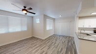This single-floor residence offers a clean, modern aesthetic carried consistently throughout its well-designed layout. The open living and dining area serves as the heart of the home, featuring durable wood-look plank flooring, a ceiling fan with light fixture, and multiple windows dressed with horizontal blinds that invite generous natural light. Vertical blinds accent a sliding door, providing access to the exterior. The kitchen is thoughtfully designed with white shaker-style cabinetry, dark granite-look countertops, a classic white subway tile backsplash, wood-look tile flooring, and stainless steel appliances including a refrigerator and range. The bedrooms are carpeted for comfort and each features a ceiling fan, ample natural light from blinds-fitted windows, and walk-in closet access. The primary bedroom connects directly to a private en-suite bathroom, while an additional full bathroom serves the rest of the home. Both bathrooms are outfitted with white cabinetry, dark countertops, large vanity mirrors with overhead lighting, and a tub-shower combination. The neutral color palette and consistent finishes throughout lend the space a cohesive, move-in-ready appeal.