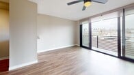 Located at 5050 Niagara Ave in the Ocean Beach neighborhood of San Diego, California, this single-floor unit offers a clean, modern aesthetic throughout. Wood-style plank flooring runs continuously across the living spaces, creating a warm, cohesive feel underfoot.

The main living area is bright and open, anchored by a ceiling fan and a large sliding glass door that opens to a private balcony enclosed by horizontal metal railings. The balcony provides elevated views of the surrounding neighborhood, including palm tree-lined streets characteristic of the San Diego coastline. Natural light flows freely through the oversized glass door, enhancing the airy ambiance of the living space.

The kitchen is efficiently laid out and well-equipped, featuring white shaker-style cabinetry with brushed nickel hardware, light-toned laminate countertops, a double-basin stainless steel sink, and stainless steel appliances including a full-size refrigerator and range. Upper and lower cabinet storage maximizes functionality within the compact footprint.

The bathroom is neatly appointed with white cabinetry, a single-sink vanity, a toilet, and a tub-shower combination. Wood-style flooring carries into the bathroom, maintaining a consistent design language throughout the unit. The overall layout is thoughtfully organized, making efficient use of the available space.