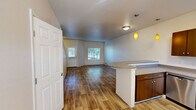 Located at 980 Ross Ave in DuPont, WA, this two-story, 2-bedroom, 2-bathroom home offers a functional and well-designed layout spread across two evenly sized floors. The main level features an open-concept living, dining, and kitchen area with warm wood-style flooring throughout. The kitchen is a standout, equipped with stainless steel appliances including a refrigerator, range, microwave, and dishwasher, complemented by rich dark cabinetry, neutral countertops, and a peninsula with pendant lighting that adds a modern touch. Natural light filters through multiple windows, creating a bright and welcoming atmosphere. A dedicated dining area flows seamlessly from the kitchen into the living space. The upper level houses both bedrooms, each featuring plush carpeting, natural light from windows with blinds, and closet storage. The primary bedroom includes a dedicated closet and access to a full bathroom. A second full bathroom serves the additional bedroom and guests, both finished with wood-style flooring and clean, neutral finishes. Additional highlights include a laundry area, hallway, and ample closet storage throughout. The home's clean, neutral palette and practical layout make it a comfortable and versatile living space.