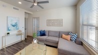This single-floor residence offers a thoughtfully designed layout that balances modern style with everyday functionality. The kitchen stands out as a centerpiece, showcasing crisp white shaker cabinetry, granite-look countertops, and a full suite of stainless steel appliances including a refrigerator, electric range, built-in microwave, and dishwasher. A pendant light fixture illuminates the sink area, while recessed lighting throughout ensures a bright and welcoming atmosphere. Rich wood-look plank flooring runs continuously through the main living areas, adding warmth and cohesion to the space. The living room is comfortable and inviting, featuring a ceiling fan, neutral-toned walls, and a large window fitted with horizontal blinds that allow for adjustable natural light and outdoor views. The open layout connects the living and kitchen areas seamlessly, creating an ideal environment for both relaxing and entertaining. A generously sized walk-in closet provides ample storage, complete with multi-level shelving rods, upper shelves, and durable wood-look flooring underfoot. Throughout the residence, clean lines, neutral finishes, and carefully chosen fixtures come together to create a cohesive, contemporary aesthetic that is both practical and visually appealing.