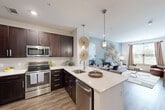 Located at 50 Woodview Way in Franklin, MA, this thoughtfully designed one-bedroom, one-bathroom unit offers a cohesive blend of modern style and everyday functionality. The open-concept layout connects the kitchen, dining, and living areas seamlessly, maximizing the efficient use of space throughout.

The kitchen is a standout feature, showcasing rich dark-brown cabinetry, quartz countertops, a full suite of stainless steel appliances, and a peninsula with seating for casual dining. Pendant lighting adds a refined touch overhead, while wood-look flooring runs throughout the main living areas, lending warmth and continuity.

The living room is bright and inviting, with a large window that draws in natural light and offers views of the surrounding greenery. The space flows naturally into the dining area, creating a comfortable, versatile environment.

The bedroom is carpeted for comfort and features multiple windows that bathe the room in natural light. A dedicated walk-in closet provides generous storage. The bathroom mirrors the home's design language with dark cabinetry, a white vanity top, and coordinating wood-look flooring.

Clean white walls and consistent finishes throughout create a calm, modern ambiance, making this Franklin residence a well-balanced and welcoming home.
