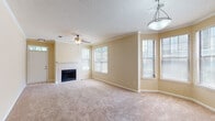 Located at 4390 Clearwater Way in Lexington, Kentucky, this single-story home offers a well-organized, comfortable layout with a variety of functional living spaces. The living room serves as the heart of the home, featuring a classic fireplace framed by a white tile surround, soft wall-to-wall carpeting, crown molding, and an abundance of natural light streaming through multiple windows with blinds. A ceiling fan and pendant light fixture add both practicality and character to the space. The kitchen is equipped with warm oak cabinetry, granite-style laminate countertops, black appliances including a range and dishwasher, a double stainless steel sink, and hardwood flooring, with open shelving providing additional storage and visual interest. The home includes multiple bedrooms, each carpeted and outfitted with ceiling fans and windows that bring in natural light. One bedroom features mirrored sliding closet doors, while another opens to an outdoor area via vertical blinds. Two full bathrooms feature hardwood flooring, granite-topped vanities with rich wood cabinetry, and tub-shower combinations with white tile surrounds. A dedicated laundry area with a full-size washer and dryer is conveniently accessible from one of the bathrooms. Throughout the home, textured ceilings and neutral warm-toned walls create a cohesive, inviting ambiance.
