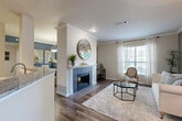 This thoughtfully designed 1-bedroom, 1-bathroom residence offers a comfortable and functional single-floor layout. The open-concept living, dining, and kitchen area forms the heart of the home, creating a seamless flow between spaces. The living room is highlighted by a classic tiled fireplace framed by a white mantel, crown molding, and hardwood-style flooring, with large windows that invite natural light throughout. The kitchen features white cabinetry, granite countertops, stainless steel appliances including a dishwasher, and a peninsula that opens to the living and dining areas. The dining area offers a distinct character with a bold blue accent wall, pendant lighting, and French doors leading to an outdoor space. The bedroom is a quiet retreat with plush carpet, crown molding, and a closet for storage. The bathroom is spacious and well-appointed, offering a granite-topped vanity with white cabinetry, a tub-shower combination, and hardwood-style flooring. Additional conveniences include two closets, two hallways, and an in-unit laundry area, providing practical storage and utility throughout this well-rounded home.