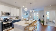 Located at 904 Lake Park Blvd N in Carolina Beach, NC, this thoughtfully designed one-bedroom, one-bathroom residence offers a cohesive coastal aesthetic and efficient single-floor layout. The open-concept kitchen and living area forms the heart of the home, where a striking two-tone kitchen showcases navy lower cabinets paired with crisp white upper cabinetry, stainless steel appliances, white quartz countertops, and a central island with pendant lighting — ideal for both meal prep and casual dining. Warm hardwood-style flooring flows throughout the main living areas, complementing the soft, neutral color palette. The living room is bright and airy, featuring French doors that invite natural light and provide outdoor access, complete with a ceiling fan overhead. The bedroom is a calm retreat, finished with plush carpet, multiple windows dressed in linen drapes, a ceiling fan, and a dedicated closet. The full bathroom is clean and functional, offering a combination tub and shower, a vanity with white countertops, navy cabinetry, and warm wood-tone flooring. The overall ambiance is light, coastal, and inviting — a comfortable home steps from the Carolina Beach lifestyle.