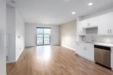 This well-appointed 2-bedroom, 2-bathroom unit at 144 Watson Rd N in Guelph, Ontario offers a thoughtfully designed open-concept layout with a clean, contemporary aesthetic throughout. Light-toned hardwood flooring flows seamlessly across the main living areas, complementing the bright, neutral colour palette that defines the space.

The kitchen is a standout feature, equipped with a full suite of stainless steel appliances — including a refrigerator, electric range, built-in microwave, and dishwasher — set against sleek white cabinetry and crisp white countertops. Recessed lighting illuminates the kitchen and living area, which opens onto a private balcony through a large sliding glass door, allowing natural light to fill the room and offering outdoor views of the surrounding neighbourhood.

The spacious primary bedroom includes a walk-in closet with built-in shelving and hanging rods, providing generous storage. The second bedroom is bright and well-proportioned, with access to a closet. Both bedrooms feature the same warm hardwood-style flooring found throughout the unit.

The two bathrooms are finished with tile flooring, white vanities with quartz-style countertops, and chrome fixtures. The primary ensuite features a frameless glass sliding shower, while the second bathroom offers a full soaker tub with tiled surround. Every detail reflects a modern, functional design ideal for comfortable everyday living.