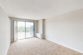 Located at 200 Ft Meade Rd in Laurel, Maryland, this one-bedroom, one-bathroom residence offers a practical and comfortable single-floor layout. The combined living and dining area is the heart of the home, featuring plush wall-to-wall carpeting, neutral-toned walls, and a textured ceiling that adds subtle character. A sliding glass door opens to a private balcony, inviting natural light and offering pleasant outdoor views of surrounding greenery. The kitchen is efficiently designed with warm wood cabinetry — including glass-front upper cabinets — a gas range, a full-size refrigerator, and a single basin sink set into a laminate countertop. Tile flooring grounds the kitchen and extends into the entryway and hallway, which also features hardwood parquet flooring at the entrance. The bedroom provides a quiet retreat with soft carpeting and ample wall space. Two closets offer generous storage throughout the unit. The bathroom is clean and straightforward, featuring a full tiled tub-shower combination and classic white fixtures. With a well-organized floor plan, this residence provides a functional and cozy living environment in a convenient Laurel, MD location.