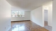 Located at 55 Park Street East in Mississauga, this well-appointed one-bedroom, one-bathroom unit offers a functional and comfortable layout across a single floor. The living room is a standout space, featuring beautifully polished parquet wood flooring in a classic herringbone pattern that runs throughout the unit. Large windows flood the living area with natural light and offer pleasant views of the surrounding greenery and neighbourhood. Baseboard heating runs along the exterior walls, ensuring warmth throughout the seasons.

The kitchen is tucked efficiently off the main living area and is equipped with stainless steel appliances, including an electric range, over-the-range microwave, and a single-basin sink. Rich dark wood cabinetry contrasts neatly with light countertops, while a white subway tile backsplash adds a clean, modern touch.

The bedroom is a calm and comfortable retreat, also featuring the same warm parquet flooring and a built-in sliding door closet for ample storage. White walls keep the space bright and versatile. A door in the bedroom provides direct access to a private outdoor area with natural views.

The bathroom is finished with neutral large-format wall tiles surrounding a full soaking tub with chrome fixtures, offering a clean and relaxing environment. A hallway connects all rooms, completing this efficient and well-designed layout.