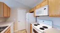 Located at 130 Cumberland Way in Pataskala, Ohio, this single-story home offers a straightforward and functional living environment. The kitchen is a standout feature, designed with efficiency in mind. Light oak cabinetry lines the upper and lower walls, providing generous storage space, while white appliances — including a coil-burner electric range, an over-the-range microwave, and a full-size refrigerator — create a cohesive, classic aesthetic. The light-toned tile flooring adds brightness to the space and is easy to maintain. A textured ceiling adds subtle dimension to the room. A six-panel interior door connects the kitchen to an adjacent area, contributing to the home's traditional architectural detailing. The neutral wall tones throughout lend a calm, versatile backdrop that complements a variety of décor styles. Overall, the home presents a tidy, no-frills interior that prioritizes practicality and ease of living, making it a solid option for those seeking a manageable, single-level residence in the Pataskala area.