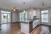 Located at 5801 Zebulon Rd in Macon, Georgia, this single-floor unit offers a well-designed, open-concept layout finished with consistent hardwood-style flooring throughout the main living areas. The open living and dining area is bright and airy, benefiting from large sliding glass doors that invite natural light and provide access to an outdoor balcony. A ceiling fan adds comfort to the living space, which flows seamlessly into the kitchen. The kitchen is thoughtfully designed in a galley style, featuring white shaker cabinetry, granite countertops, a subway tile backsplash, stainless steel appliances including a refrigerator, range, and microwave, and a peninsula that doubles as a breakfast bar. The bedrooms are carpeted for comfort and receive ample natural light through large windows. The bathrooms are clean and well-appointed, each featuring white cabinetry with granite countertops, a tub-shower combination, and hardwood-style flooring. A dedicated in-unit laundry room accommodates a full-size washer and dryer, adding everyday convenience. Neutral wall tones and clean finishes throughout create a cohesive, move-in-ready aesthetic well suited for comfortable living.