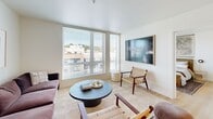Located at 1765 22nd Ave S in Seattle's Judkins Park neighborhood, this thoughtfully designed two-bedroom, two-bathroom residence offers a clean, modern aesthetic throughout. Light wood flooring flows seamlessly across the entire single-floor layout, creating a cohesive and inviting atmosphere.

The open-concept kitchen and living area serves as the heart of the home. The kitchen features light wood cabinetry extending to the ceiling, a textured tile backsplash, stainless steel appliances including a full-size refrigerator, range, microwave, and dishwasher, and a dark stone-topped island with bar seating. An in-unit stacked washer and dryer adds everyday convenience.

The living room is bathed in natural light from large windows that frame views of the surrounding Seattle neighborhood, creating a bright and airy feel. Both bedrooms are well-proportioned, with the primary bedroom offering a walk-in closet with wire shelving. Large windows in both bedrooms bring in ample daylight.

The two bathrooms are finished with light wood vanities and clean white fixtures. One bathroom features a soaking tub with shower combination. The overall design palette of warm whites and natural wood tones gives the entire residence a calm, contemporary character.