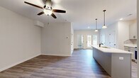 Located at 15 Millswood Drive in Clarksville, Tennessee, this well-appointed single-story home offers a thoughtfully designed layout with one bedroom, two bathrooms, a dedicated closet, and in-unit laundry. The open-concept living and kitchen area serves as the heart of the home, featuring stylish luxury vinyl plank flooring, a ceiling fan, and a glass-paneled door that invites natural light. The kitchen is a standout, equipped with gray shaker-style cabinetry, a tile backsplash, stainless steel appliances including a range, microwave, and French door refrigerator, and a central island with a white countertop and built-in sink, illuminated by pendant lighting overhead. The spacious primary bedroom is finished with plush carpet, a ceiling fan, and a window offering natural light and outdoor views. The en-suite bathroom includes a vanity with white countertops, dark hardware accents, a bathtub, and wood-look flooring. A secondary half bath provides added convenience. Additional spaces include a carpeted secondary bedroom area, a dedicated closet, and a separate laundry room. Neutral tones and clean finishes throughout give the home a bright, move-in-ready aesthetic.