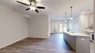Located at 15 Millswood Drive in Clarksville, Tennessee, this well-appointed single-story home offers a thoughtfully designed layout with one bedroom, two bathrooms, a dedicated closet, and in-unit laundry. The open-concept living and kitchen area serves as the heart of the home, featuring stylish luxury vinyl plank flooring, a ceiling fan, and a glass-paneled door that invites natural light. The kitchen is a standout, equipped with gray shaker-style cabinetry, a tile backsplash, stainless steel appliances including a range, microwave, and French door refrigerator, and a central island with a white countertop and built-in sink, illuminated by pendant lighting overhead. The spacious primary bedroom is finished with plush carpet, a ceiling fan, and a window offering natural light and outdoor views. The en-suite bathroom includes a vanity with white countertops, dark hardware accents, a bathtub, and wood-look flooring. A secondary half bath provides added convenience. Additional spaces include a carpeted secondary bedroom area, a dedicated closet, and a separate laundry room. Neutral tones and clean finishes throughout give the home a bright, move-in-ready aesthetic.