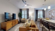 This single-floor residence offers a thoughtfully designed layout encompassing one bedroom and one and a half bathrooms. The living area is bright and welcoming, featuring wood-style flooring, multiple windows dressed with elegant draping curtains and blinds, and a ceiling fan overhead. A dedicated dining space adjacent to the living room provides a comfortable area for entertaining, highlighted by a marble-topped table and natural light from a large window.

The kitchen is a standout feature, showcasing dark espresso cabinetry, light granite countertops, a tiled backsplash, stainless steel appliances, and a central island with bar seating. Track and pendant lighting add both function and visual interest throughout the space.

The bedroom is a serene retreat with carpeted flooring, soft neutral tones, and direct access to an outdoor balcony through glass French doors. The ensuite bathroom is well-appointed, offering a double-sink vanity with granite countertops, dark cabinetry, a glass-enclosed walk-in shower with tile surround, and access to a walk-in closet. A separate half-bath provides added convenience for guests.