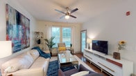This single-story, 2-bedroom, 2-bathroom residence features a thoughtfully designed open-concept layout that seamlessly connects the living, dining, and kitchen areas. The living room is anchored by a ceiling fan, wood-style flooring, and large windows that invite natural light, creating a bright and welcoming atmosphere. A second living area configuration is also visible, offering flexible furniture arrangements to suit various lifestyles.

The kitchen is a functional centerpiece, featuring dark espresso cabinetry, granite countertops, black appliances, a double-basin sink, and pendant lighting that adds a refined touch. A peninsula counter provides casual dining space, while a dedicated dining area nearby accommodates a full table setting.

Both bedrooms are generously proportioned, each outfitted with ceiling fans, plush carpeting, and windows with blinds that allow for adjustable natural light. The primary bedroom includes an en-suite bathroom and decorative glass-panel closet doors, adding an elegant detail. The second bedroom offers ample space and similar window coverage.

The bathrooms are clean and efficiently designed, with one featuring a walk-in shower with granite-topped vanity. Throughout the unit, neutral tones and consistent finishes create a cohesive and comfortable living environment.