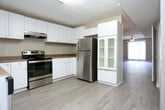 This two-floor residence offers a practical and comfortable layout spread across multiple well-defined living spaces. The main living area features durable wood-look flooring, a ceiling fan with integrated lighting, and a built-in fireplace with a tiled hearth — serving as a natural focal point of the room. A sliding glass door floods the space with natural light and provides access to an outdoor area. A secondary living or flex space on the upper level is carpeted and bright, with large windows dressed in vertical blinds that allow generous light to filter through.

The kitchen is well-appointed with white cabinetry, dark granite-style countertops, and a full suite of stainless steel appliances including a range, dishwasher, and refrigerator. Light-toned flooring and multiple windows contribute to a bright, functional workspace. A door within the kitchen provides convenient exterior access.

The bedrooms are carpeted and finished with neutral tones, ceiling fans, and vertical blinds on the windows. A staircase connects the two floors, visible through a doorway in one of the upper-level rooms. The bathroom includes a full tub and shower enclosure with a chrome towel bar, complemented by a separate water closet for added privacy. Throughout, textured ceilings and clean white trim tie the overall aesthetic together.