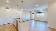Located at 3335 N 185th Ct in Elkhorn, Nebraska, this 3-bedroom, 2-bathroom single-floor home offers a thoughtfully designed open-concept layout. The kitchen serves as a central hub, featuring a large island with a granite countertop, undermount sink, pendant lighting with gold-toned hardware, white shaker cabinetry, and stainless steel appliances including a range and over-the-range microwave. Light wood-style flooring flows seamlessly from the kitchen into the spacious living area, which is filled with natural light from large windows and a glass-panel door that overlooks the surrounding neighborhood. The primary bedroom is a comfortable retreat, connected to a private bathroom with a granite-topped vanity and wood-look flooring. The secondary bedrooms feature plush carpeting, generous closet space, and large windows that bring in abundant natural light and exterior views. A second full bathroom includes a tub-shower combo and granite vanity. The dedicated laundry room is equipped with a washer and dryer and includes additional cabinetry for storage. Clean white walls, recessed lighting, and consistent finishes throughout create a bright, modern, and cohesive aesthetic across the entire home.