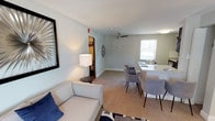 This single-floor residence offers a thoughtfully arranged layout with a cohesive, neutral color palette that creates a calm and livable atmosphere throughout. The combined living and dining area serves as the heart of the unit, featuring soft carpeting, light gray walls, crown molding, and a ceiling fan overhead. A dining table with modern gray chairs sits adjacent to a granite-topped counter, while natural light filters in through a window. Decorative wall accents and a table lamp add warmth to the space.

The kitchen is well-equipped with rich, dark wood cabinetry, a white subway tile backsplash, and hardwood-style flooring. Black appliances, including a gas range, refrigerator, and over-the-range microwave, complement the granite countertops. A window brings in additional natural light.

The unit includes multiple bedrooms, each finished with plush carpeting and neutral walls. The bedrooms feature windows that admit natural light, ceiling fans or overhead lighting, and closet storage. One bedroom includes a radiator, adding character to the space.

The bathroom is clean and functional, featuring a pedestal sink, a mirrored medicine cabinet, a tub-shower combination, and a window for ventilation and light.
