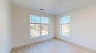 Located in Spring Lake, Michigan, this well-designed one-bedroom, one-bathroom unit offers a clean, modern aesthetic throughout. The open-concept kitchen and living area serves as the heart of the space, featuring a central island with a white quartz countertop and built-in sink, warm-toned flat-panel cabinetry, white subway tile backsplash, and a full suite of stainless steel appliances including a refrigerator, range, microwave, and dishwasher. Light hardwood flooring runs seamlessly across the entire unit, complementing the crisp white walls and creating a bright, cohesive atmosphere. Recessed lighting in the kitchen adds a polished touch. The living area is open and versatile, providing ample room for various furniture arrangements. The bedroom is comfortably sized, filled with natural light through large windows fitted with horizontal blinds that offer views of the surrounding neighborhood. The bathroom features a tub-shower combination, a floating wood vanity with a white countertop, and brushed nickel fixtures and grab bar accents. Throughout the unit, the design prioritizes simplicity and functionality, resulting in a fresh, contemporary living environment.
