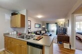 Located at 2200 Great Northern Ave in Missoula, Montana, this one-bedroom, one-bathroom residence offers a well-designed single-floor layout that maximizes every square foot. The open-concept living and dining area flows seamlessly from the kitchen, creating an inviting, connected space ideal for everyday living. The kitchen features warm honey-toned wood cabinetry, a peninsula with a double-basin sink, stainless steel dishwasher, and ample counter space with neutral laminate surfaces — all opening directly to the living area. Durable wood-look flooring runs throughout the main living spaces, adding warmth and continuity.

The living room is bright and welcoming, anchored by a sliding glass door that floods the room with natural light and provides direct access to a private patio with outdoor views. The bedroom is a calm retreat with plush carpeting, a large window overlooking greenery, and generous closet space — three closets are included throughout the unit. The bathroom offers a wide vanity with wood cabinetry, a large mirror, and wood-look flooring. A dedicated in-unit laundry area with full-size washer and dryer hookups adds exceptional convenience. This residence combines functional design with comfortable living in a well-appointed Missoula community.