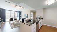 Located on the iconic Wilshire Boulevard in the heart of Los Angeles, this 2-bedroom, 2-bathroom residence offers a well-designed open-concept layout with modern finishes throughout. The kitchen is outfitted with sleek white cabinetry, dark granite countertops, stainless steel appliances including a refrigerator, range, microwave, and dishwasher, and flows seamlessly into the combined living and dining area. The living room features warm hardwood flooring, a bold navy accent wall, floor-to-ceiling windows that invite abundant natural light, and city views that bring the urban energy of Los Angeles indoors. Track lighting adds a contemporary touch to the shared living space. The primary bedroom is generously sized, offering a dedicated closet and warm neutral tones, while the second bedroom enjoys large windows with city views. Both bathrooms are finished with wood-style flooring, white vanities, large mirrors, and full bathtub-shower combinations — one featuring accessibility grab bars. Two closets provide practical storage throughout. The overall ambiance is clean, contemporary, and well-suited to urban living in one of Los Angeles' most well-known corridors.