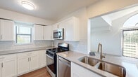 Located on Saffron Lane in Grand Rapids, Michigan, this single-floor residence offers a clean, modern aesthetic throughout its well-designed layout. The kitchen is a standout feature, showcasing crisp white shaker cabinetry, light quartz countertops, and a classic subway tile backsplash. A full suite of stainless steel appliances—including a gas range, built-in microwave, dishwasher, and refrigerator—adds a sleek, functional appeal, while wood-look flooring and a double-basin sink with a brushed gold faucet complete the space with refined detail. The open floor plan connects the kitchen to the living area, which is distinguished by soaring vaulted ceilings, a ceiling fan with a gold finish, and a dramatic arched window that floods the room with natural light. Plush neutral carpeting runs throughout the living and bedroom areas, creating a warm and comfortable atmosphere. The bedrooms are generously sized, with large windows offering pleasant outdoor views of the surrounding greenery. One bedroom features a ceiling fan and an expansive window framing a lush landscape view, while additional rooms provide versatile, open spaces suitable for a variety of uses. Throughout the residence, a consistent neutral color palette, ample natural light, and thoughtful finishes contribute to a bright, move-in-ready environment.