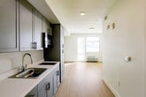 Located at 2358 Alum Rock Ave in San Jose, California, this efficiently designed single-floor unit offers a clean, contemporary layout that maximizes every square foot. The open-concept interior flows seamlessly from the kitchen into the living area, creating a functional and cohesive living space.

The kitchen is a standout feature, outfitted with sleek gray shaker-style cabinetry extending from floor to ceiling, providing generous storage. White countertops offer a crisp contrast, while stainless steel appliances — including a full-size refrigerator, built-in microwave, and an electric cooktop — complete the modern setup.

Light-toned luxury vinyl plank flooring runs throughout the main living area, lending a clean and contemporary aesthetic. The living space is bathed in natural light courtesy of large windows fitted with horizontal blinds, with a wall-mounted HVAC unit ensuring year-round comfort.

The bathroom is thoughtfully appointed with a gray vanity, white countertop, a large mirror, and safety grab bars, indicating accessibility-conscious design. Recessed lighting and a bright, neutral color palette throughout the unit contribute to an airy, well-lit ambiance. The entry corridor connects all areas efficiently, completing this well-planned and move-in-ready space.
