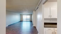 Located at 293 Turnpike Rd in Westborough, MA, this single-floor, three-bedroom, two-bathroom residence offers a well-organized layout across a generously sized floor plan. The open living room is a standout feature, showcasing dark hardwood-style flooring, a textured ceiling, and a large sliding glass door dressed with vertical blinds that floods the space with natural light and provides access to an outdoor area. Adjacent to the living room, the kitchen is equipped with stainless steel appliances including a gas range and full-size refrigerator, complemented by white cabinetry, dark granite-style countertops, and a sink — all set atop matching hardwood-style flooring. The three bedrooms are carpeted for comfort, each offering closet space and windows with vertical blinds that bring in ample natural light. The generously sized primary bedroom provides a notably spacious retreat. Both bathrooms are finished with white vanity cabinetry, light countertops, large mirrors, and hardwood-style flooring, giving them a clean, bright appearance. A hallway and closet complete the practical layout. Throughout the home, neutral tones and consistent finishes create a cohesive, move-in-ready ambiance.