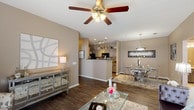 This single-story, 2-bedroom, 2-bathroom residence is designed with an open-concept layout that connects the living, dining, and kitchen areas into a cohesive, functional space. The living room features dark hardwood-style flooring, a ceiling fan with light fixture, and French doors that invite natural light and provide outdoor access. A mirrored sideboard and glass coffee table complement the room's contemporary aesthetic.

The adjacent dining area accommodates a round glass table beneath a modern pendant light, while the galley-style kitchen offers ample cabinetry in a two-tone gray finish, granite-style countertops, a stainless steel sink, and black appliances including a range, microwave, and refrigerator. Track lighting overhead enhances the kitchen's functionality.

Both bedrooms are carpeted and generously sized, each with natural light from windows with blinds and ceiling fans. The primary bedroom provides a serene retreat, while the secondary bedroom offers comparable comfort. Each bedroom is served by its own full bathroom, both featuring vanities with light countertops, large mirrors, and tub-shower combinations with neutral-toned walls and wood-style flooring.
