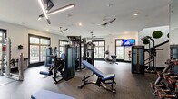 Located at 300 Dalhausser Lane in Oviedo, FL, this two-story fitness center is a comprehensively equipped facility designed to support a wide range of workout needs. The lower level provides a solid foundation for the facility, while the more expansive upper floor offers additional training space, together creating a well-organized and functional environment.

The gym areas are outfitted with professional-grade Matrix equipment, including multi-station cable machines, weight benches, a full rack of dumbbells, and an assortment of cardio machines such as treadmills, ellipticals, and stair climbers. Large black-framed windows throughout the gym spaces flood the floors with natural light and provide outdoor views, contributing to an energizing atmosphere. Ceiling fans and modern lighting fixtures — including linear LED pendants — maintain comfort and visibility across the workout areas.

Design details such as exposed wood beams, a bold teal ceiling accent, and a vibrant graphic accent wall add visual character to the space. Full-length mirrors in the free weights area enhance both functionality and the sense of openness. Rubber flooring throughout ensures durability and safety.

The facility also includes a cedar-lined sauna, offering a dedicated recovery space. Supporting amenities include multiple utility rooms, two bathrooms, a connecting hallway, and two staircases providing convenient access between floors.