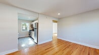 Located at 33 Fair Lawn Ave in Fair Lawn, NJ, this single-floor home offers five bedrooms and one bathroom within a well-utilized layout. Warm hardwood flooring runs throughout the living areas and bedrooms, lending a consistent and inviting character to the space. The living room greets you at the entrance, featuring a large front-facing window that draws in natural light, a classic radiator, and a wall-mounted AC unit. Recessed lighting further brightens the open feel of the main area. The kitchen is efficiently designed in a galley style, outfitted with white shaker cabinetry, granite-style countertops, and a full suite of stainless steel appliances including a gas range, microwave, and refrigerator. Light flows in through a window overlooking greenery outside. The five bedrooms are finished with the same warm hardwood floors and neutral-toned walls, offering clean, versatile spaces. The bathroom is crisp and fully tiled in white subway tile, featuring a tub/shower combination, a white vanity with medicine cabinet mirror, stone-look floor tile, and a charming cast iron radiator. Throughout the home, clean white trim and neutral walls create a bright, cohesive aesthetic.