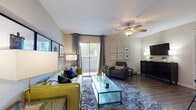 This single-floor residence offers a thoughtfully designed layout that balances comfort and functionality throughout its key living areas. The living room serves as the heart of the home, featuring wood-style flooring, a ceiling fan with light fixture, and a sliding glass door that opens to a private balcony, allowing natural light and outdoor views to flow freely into the space. The room provides ample space for relaxed seating arrangements and is complemented by neutral-toned walls that lend a clean, versatile aesthetic.

Adjacent to the living area, the dining space accommodates a round table with seating and is accented by bold artwork and decorative wall pieces, adding a touch of personality to the room. The kitchen is well-equipped with white shaker-style cabinetry, light countertops, a stainless steel sink and dishwasher, and a black refrigerator, all set over wood-style flooring for a cohesive look.

The bedroom is a serene retreat featuring plush carpeting, a ceiling fan, a large window with outdoor views, and generous space for bedroom furnishings. The full bathroom includes a white vanity with storage, a large mirror with lighted surround, and a tub-shower combination with a stylish patterned curtain — completing this well-rounded and comfortable living space.