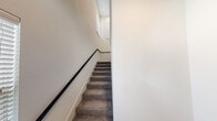This two-story residence offers a thoughtfully designed layout with modern finishes and practical amenities throughout. The main living level features an open-concept living and dining area with light wood-look flooring, a ceiling fan, and recessed lighting. The kitchen is outfitted with granite countertops, taupe cabinetry, a subway tile backsplash, stainless steel appliances including a refrigerator and dishwasher, and a built-in wine rack — creating a functional and stylish space for cooking and entertaining. A carpeted staircase with a dark wood handrail connects both floors, with natural light filtering in from a nearby window. The upper level hosts carpeted bedrooms filled with natural light through slatted blinds. The bathrooms are finished with wood-look vinyl flooring, granite vanity countertops, and marble-style tile surrounds — one featuring a walk-in glass-enclosed shower and another with a soaking tub and shower combo. A dedicated laundry room with a full-size washer and dryer adds everyday convenience. The attached garage provides secure parking with interior access, completing this well-rounded and move-in-ready home.