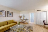 Located at 1850 NE 48th St in Pompano Beach, Florida, this one-bedroom, one-bathroom unit offers a practical and well-organized single-floor layout. Light-toned tile flooring runs consistently throughout the space, lending a clean, cohesive aesthetic. The combined living and dining area forms the heart of the unit, featuring a textured ceiling, neutral walls, and a window that allows natural light to filter in with views of the surrounding greenery. A hallway connects the main living area to the private spaces beyond. The galley-style kitchen is efficiently designed with light wood cabinetry, granite-look countertops, a double sink, and a full suite of white appliances, including a dishwasher, range, and refrigerator. A window above the counter brings in additional natural light. The bedroom is comfortably sized, featuring tile flooring, a textured ceiling, a window with blinds, and access to a louvered-door closet. The unit also benefits from three closets in total, providing ample storage throughout. The bathroom is clean and functional, outfitted with a white vanity, mirrored medicine cabinet, tiled flooring, and a shower-tub combination. The overall ambiance is bright, neutral, and move-in ready, well-suited for comfortable Florida living.