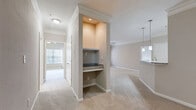 Located at 4045 George Busbee Pkwy NW in Kennesaw, GA, this well-appointed 2-bedroom, 2-bathroom residence offers a thoughtfully designed single-floor layout with a warm, neutral color palette and crown molding throughout. The open-concept living and dining area is spacious and inviting, featuring plush carpet, a ceiling fan with light fixture, and a door leading directly to a private balcony with outdoor views. A built-in desk nook with granite countertop adds a functional touch to the main living space. The kitchen is outfitted with white shaker cabinetry, granite countertops, a gray subway tile backsplash, wood-look flooring, and stainless steel appliances, including a full-size refrigerator and dishwasher. Pendant lighting over the counter enhances the modern aesthetic. The primary bedroom is generously sized, bathed in natural light from large windows, and features crown molding and a ceiling fan. Both bedrooms are served by their own bathrooms, each finished with wood-look tile flooring, white tub-shower combinations accented by black tile detailing, and granite vanity countertops. The residence also includes an impressive six closets, an in-unit laundry area, and a utility room, ensuring abundant storage and everyday convenience throughout.