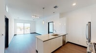 Located at 525 N Wilton Pl in Los Angeles, this modern single-floor unit showcases a sleek, contemporary design throughout. The open-concept living area flows seamlessly from the kitchen, featuring light hardwood-style flooring, crisp white walls, and bold dark baseboards that create a clean, high-contrast aesthetic.

The kitchen is a standout feature, centered around a large island with a stainless steel sink, white flat-panel cabinetry, and light quartz countertops. Stainless steel appliances — including a gas range with a stainless backsplash, dishwasher, refrigerator, and microwave — complete the chef-ready space. Pendant lighting above the island and track lighting in the living area add both function and style. A sliding glass door opens to a balcony, filling the living space with natural light and outdoor views of the Los Angeles skyline.

The bedrooms are generously proportioned with large windows framing sweeping city views, recessed lighting, and ample wall space. The bathrooms feature modern floating vanities with white cabinetry, integrated sinks, illuminated mirrors, and wood-look flooring. One bathroom includes access to a well-organized walk-in closet with built-in shelving. The overall ambiance is clean, minimal, and move-in ready.