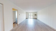 This 1-bedroom, 1-bathroom unit at 349 N Pearl St in Brockton, MA offers a thoughtfully laid-out single-floor design. The spacious living room is a standout feature, showcasing light-toned hardwood-style flooring, neutral white walls, and a sliding glass door that opens to a balcony, filling the room with natural light and outdoor views. A wall-mounted air conditioning unit and baseboard heating provide year-round climate comfort. The kitchen is efficiently designed with warm-toned wooden cabinetry extending to the ceiling for ample storage, complemented by laminate countertops, a stainless steel sink, and white appliances including a refrigerator, range, and dishwasher. The bedroom offers plush carpeting, a window with outdoor views, baseboard heating, a wall-mounted AC unit, and a built-in closet with louvered doors for generous storage. The bathroom is clean and functional, featuring a full tub-shower combination with white tile surround, a vanity with white cabinetry, and light tile flooring. Throughout the unit, the consistent neutral palette and clean finishes create a bright, cohesive living environment.