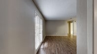 Located at Broadway Commons in Garland, TX, this 2-bedroom, 2-bathroom single-floor home offers a practical and well-appointed layout. Rich wood-look flooring flows consistently throughout, lending warmth and visual cohesion to every room.

The living area is a bright, open space anchored by French doors with white plantation shutters that invite abundant natural light. A textured ceiling and clean neutral walls give the room a simple, welcoming character.

The galley-style kitchen is efficiently designed with warm wood cabinetry, granite-look countertops, a mosaic tile backsplash, and white appliances including a range, dishwasher, and refrigerator — offering a functional cooking space with an attractive finish.

Both bedrooms continue the wood-look flooring and feature ceiling fans with light fixtures, windows with blinds for natural light and privacy, and access to closets. The primary bedroom includes a walk-in closet with built-in shelving for organized storage.

The bathrooms are finished with wood cabinetry, granite-look vanity tops, and tub-shower combinations. A dedicated hallway and entrance area connect the home's spaces cleanly. Neutral gray tones throughout create a calm, cohesive ambiance suited to a variety of styles.