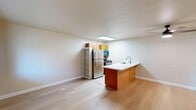 Unit 21 at 501 Michigan Blvd in West Sacramento, CA offers a well-designed single-floor layout with one bedroom and two bathrooms. The open-concept living, dining, and kitchen area creates a cohesive and functional living space. Light wood laminate flooring runs throughout the main living areas, contributing to a bright and clean aesthetic.

The kitchen is a standout feature, equipped with stainless steel appliances including a refrigerator and gas range, warm wood cabinetry, and a generous peninsula counter topped with striking white marble-style quartz. A skylight above the kitchen floods the space with natural light. The kitchen also transitions to a galley-style prep area with tile flooring and extended counter space.

The bedroom is a comfortable, well-proportioned room featuring light wood flooring, a ceiling fan with light fixture, and a large window that invites natural light and offers views of the surrounding neighborhood. A full-width sliding closet provides ample storage. Two bathrooms serve the unit, with tile flooring lending a practical, clean finish.

A hallway connects the main spaces and includes built-in shelving for additional storage. The unit's neutral warm tones throughout create a calm, inviting atmosphere suited for everyday living.