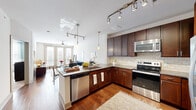 This single-floor residence offers a thoughtfully designed open-concept layout that seamlessly connects the kitchen, dining, and living areas. The kitchen is a standout feature, boasting rich dark wood cabinetry, granite countertops, a tile backsplash, and a full suite of stainless steel appliances including a range, microwave, and dishwasher. A peninsula with bar seating and elegant pendant lighting makes it ideal for both casual dining and entertaining. Track lighting overhead provides additional illumination throughout the cooking and living spaces.

The living area is bright and welcoming, anchored by large French doors that flood the space with natural light and open to an outdoor area. Warm hardwood flooring runs throughout the main living spaces, adding a sense of continuity and warmth. Multiple panel doors provide access to additional rooms and closets, offering generous storage throughout.

The bedroom is a serene retreat, featuring plush carpeting, a ceiling fan, and a vibrant accent wall that adds character to the space. Natural light filters in through large windows dressed with stylish curtains. The en-suite bathroom includes a soaking tub, a separate walk-in shower, a rich wood vanity with granite countertops, and a spacious walk-in closet, completing this comfortable and well-finished residence.