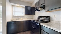 Located at 1250 Crescent Heights Rd in Marion, Ohio, this two-floor residence offers a practical and well-maintained layout spread across two levels. The kitchen is a standout feature, showcasing dark navy cabinetry paired with light granite-style countertops, a black electric range with overhead ventilation, and a double-basin sink positioned beneath a window that allows natural light to filter in. The kitchen's L-shaped configuration provides ample counter and storage space for everyday use.

Throughout the living areas and bedrooms, wood-look vinyl plank flooring in warm and cool gray tones creates a cohesive, low-maintenance aesthetic. The living area benefits from large vertical blinds covering a full-height window or sliding door, inviting natural light and offering outdoor views. Neutral gray walls throughout the home provide a clean, versatile backdrop.

The bedrooms are generously sized, each featuring closet storage — including reach-in closets with built-in rods — and windows that bring in natural light. The bathroom is finished with a white vanity cabinet, integrated sink, and a mirrored medicine cabinet above, offering both functionality and clean styling. A staircase connects the two floors, with closet access conveniently located near the landing. The overall ambiance is clean, updated, and move-in ready.