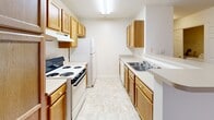 Located at 900 Poplar Forest Rd in Farmville, Virginia, this single-floor unit offers a practical and well-organized layout designed for comfortable everyday living. The open floor plan connects the living and dining areas, both finished with warm neutral-toned carpeting that extends throughout the main living spaces. A pass-through window connects the living area to the kitchen, enhancing the sense of openness.

The galley-style kitchen is efficiently designed, featuring warm wood cabinetry on both sides, ample counter space with light-toned laminate surfaces, a stainless steel double sink, and white appliances including a coil-top range and a full-size refrigerator. Light tile flooring completes the kitchen's clean and functional aesthetic.

The bedrooms are generously proportioned, each featuring plush carpeting and windows that allow natural light to filter in. The primary bedroom includes a spacious double-door closet and direct access to a hallway bath. Additional rooms offer flexibility for use as secondary bedrooms or office space. The bathroom is outfitted with a full tub and shower combination with a grab bar, a wood-cabinet vanity with a single sink, and a large mirror. An electrical panel is conveniently accessible in the main hallway. The overall interior presents a clean, move-in-ready environment with a neutral palette throughout.
