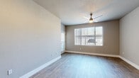 This 2-bedroom, 2-bathroom residence offers a thoughtfully designed single-floor layout with consistent, modern finishes throughout. Wood-look plank flooring flows seamlessly across all living areas, complementing the neutral gray wall tones that create a clean, contemporary aesthetic.

The living room is a bright and open space anchored by a ceiling fan with light fixture and large windows dressed with vertical blinds, allowing ample natural light to fill the room. A secondary window and access door further enhance the airy feel of this central gathering area.

The kitchen is efficiently designed with white shaker-style cabinetry, white quartz countertops, a tile backsplash, and a full suite of stainless steel appliances including a refrigerator, range, and over-the-range microwave.

Both bedrooms are well-sized with large windows fitted with vertical blinds that bring in natural light. The primary bedroom includes a dedicated closet outfitted with built-in shelving and hanging rods for organized storage.

Each of the two bathrooms features matching gray vanity cabinetry, white quartz countertops, a framed mirror with overhead vanity lighting, and a tub-shower combination finished with large-format marble-look tile surrounds. Wood-look flooring extends into both bathrooms, tying the design together cohesively throughout the entire residence.